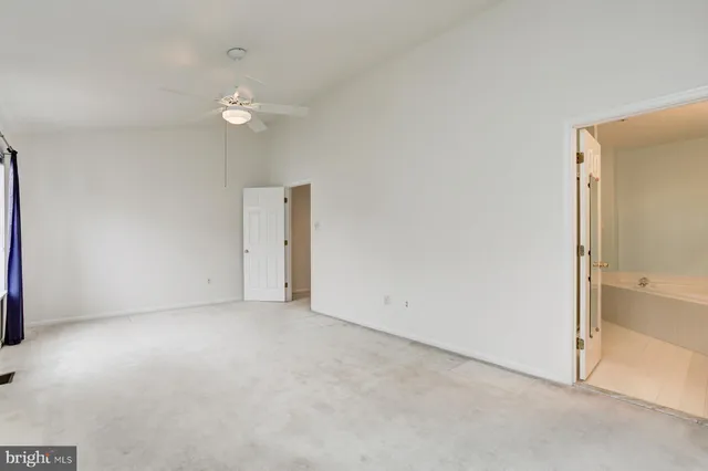 an empty room with a bathroom and a ceiling fan