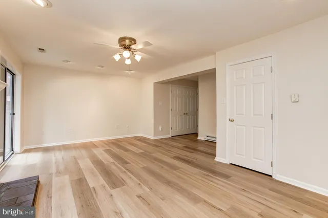 a view of empty room with wooden floor and fan