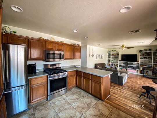 1109 Rebecca Avenue Ridgecrest, CA 93555 - Photo 16 of 50 a kitchen with stainless steel appliances granite countertop a stove top oven a sink dishwasher a refrigerator and white cabinets with wooden floor
