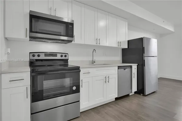 a kitchen with cabinets stainless steel appliances and a wooden floor
