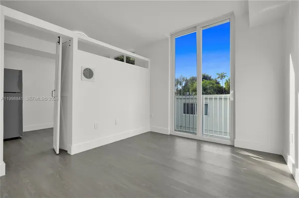 a view of a small space with wooden floor and a large window