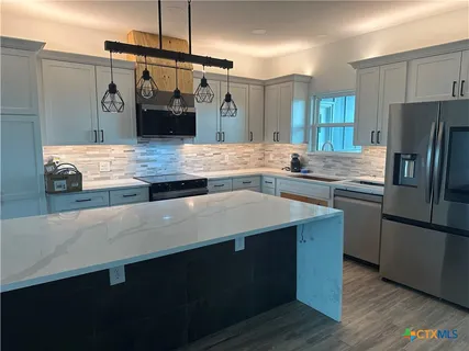 a kitchen with kitchen island a sink appliances and cabinets