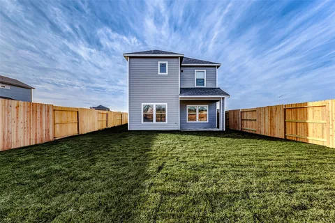 a view of a house with backyard and wooden fence