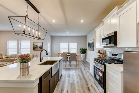 a kitchen with stainless steel appliances a table chairs refrigerator and microwave