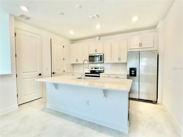 a kitchen with kitchen island a white counter top space cabinets and stainless steel appliances
