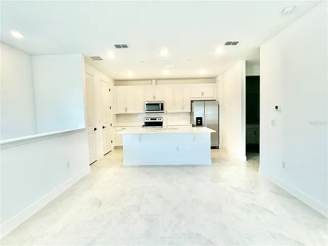 a large white kitchen with kitchen island a stove a sink and a refrigerator