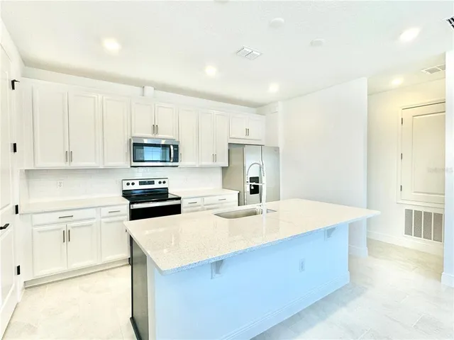 a kitchen with a sink a stove a refrigerator and white cabinets