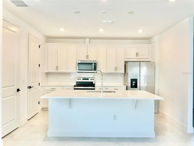 a kitchen with stainless steel appliances a refrigerator a stove a sink and white cabinets