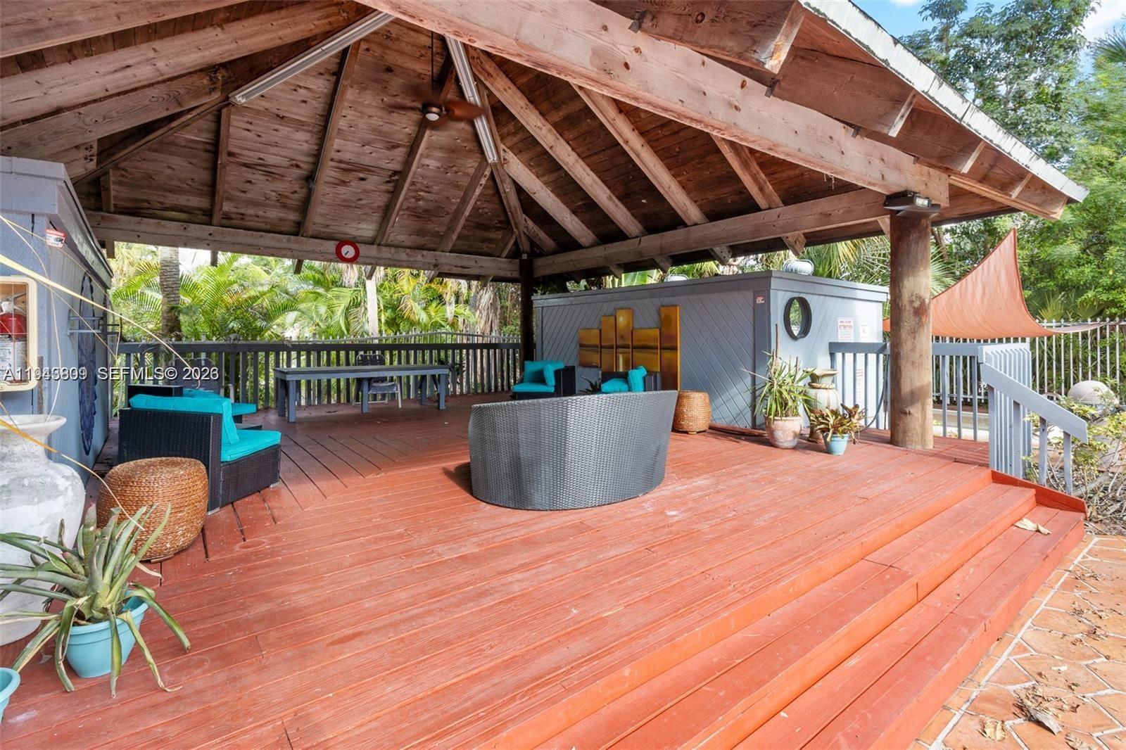 8331 Southwest 157th Avenue, Unit 409 Miami, FL 33193 - Photo 17 of 19 a view of a patio with table and chairs under an umbrella with a wooden fence
