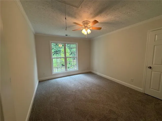 an empty room with windows and chandelier fan