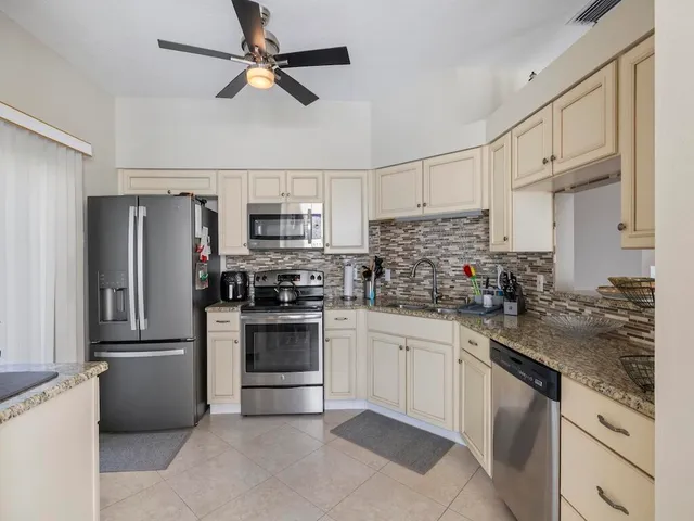 a kitchen with stainless steel appliances granite countertop a refrigerator a stove a sink and white cabinets