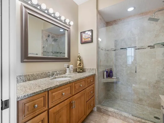 a bathroom with a granite countertop sink a mirror and a shower