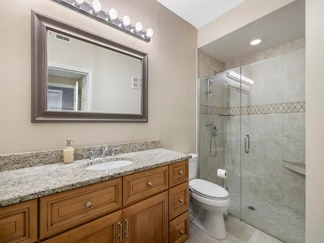 a bathroom with a granite countertop sink a toilet and a mirror