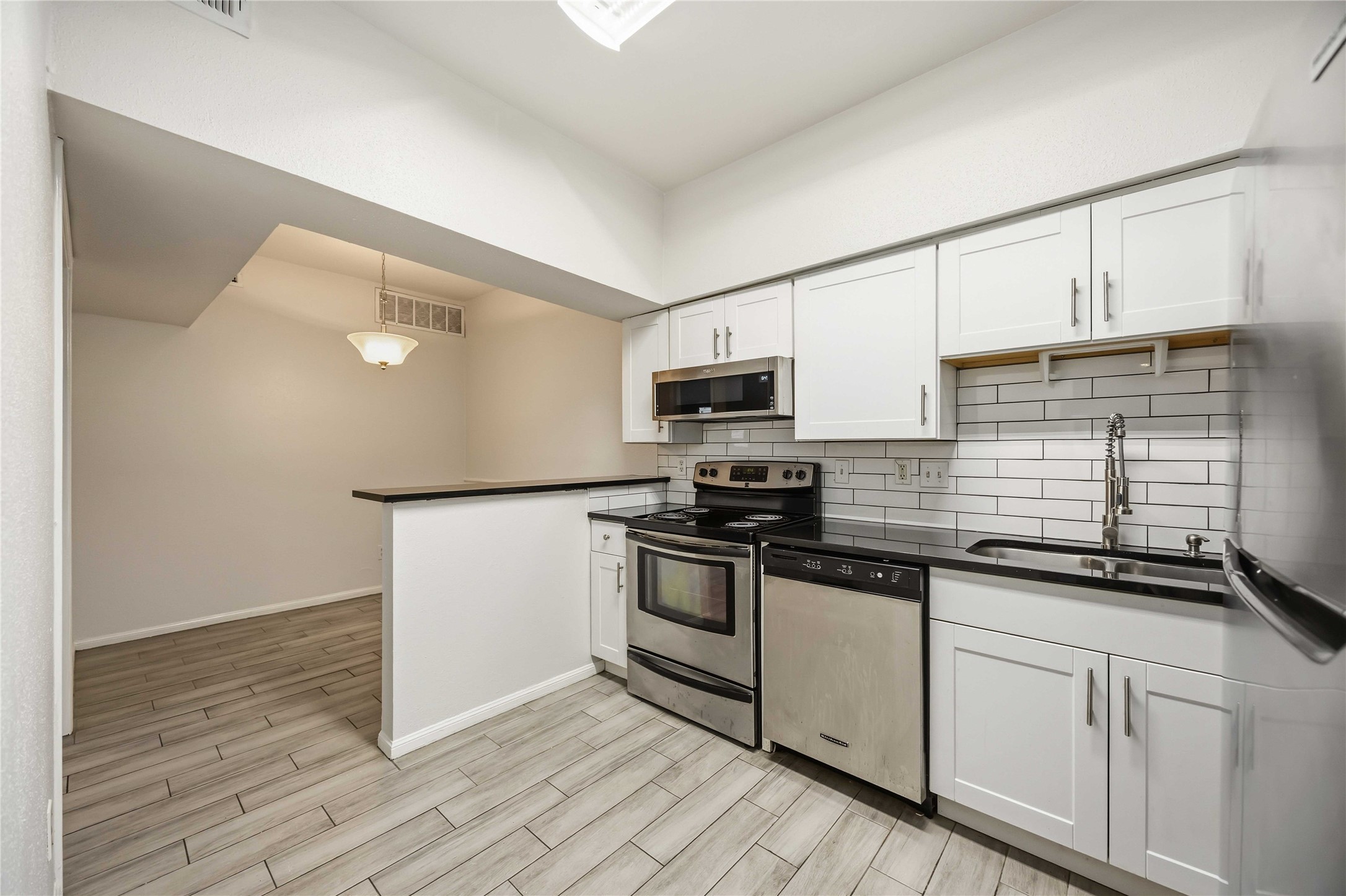 2100 Tanglewilde Street, Unit 531 Houston, TX 77063 - Photo 7 of 25 a kitchen with stainless steel appliances granite countertop a sink a stove a microwave and cabinets