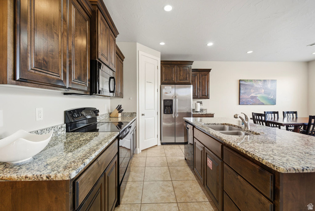 4269 Razor Drive Washington, UT 84780 - Photo 2 of 50 Kitchen with black appliances, dark brown cabinetry, light stone countertops, a kitchen island with sink, and recessed lighting
