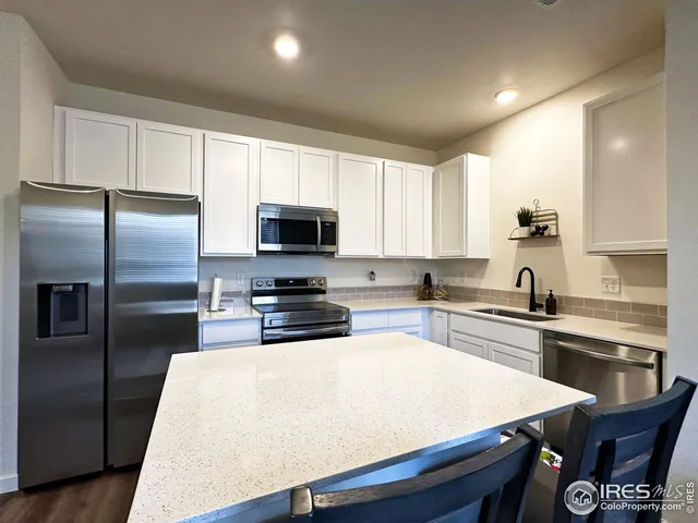 a kitchen with stainless steel appliances a stove a sink a refrigerator a microwave and cabinets