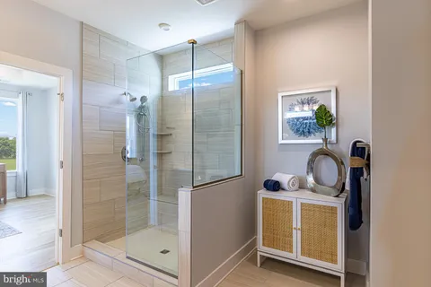 a bathroom with a shower a mirror and a glass door