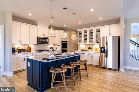 a kitchen with stainless steel appliances granite countertop a table chairs refrigerator and microwave