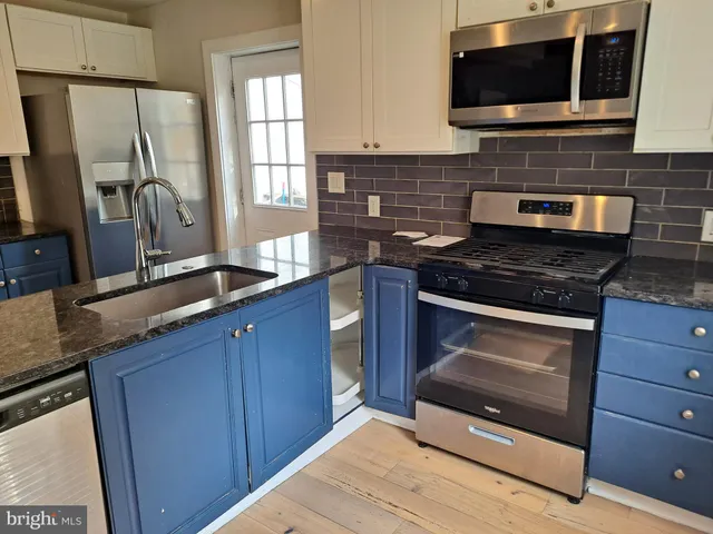 a kitchen with kitchen island granite countertop wooden cabinets and stainless steel appliances