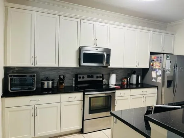 a kitchen with white cabinets and black appliances
