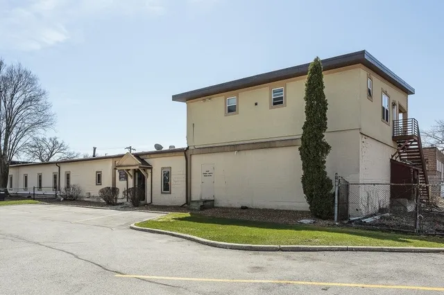 a view of a white house with large windows and a small yard