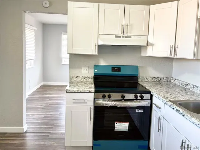 a kitchen with stainless steel appliances granite countertop a sink stove and white cabinets