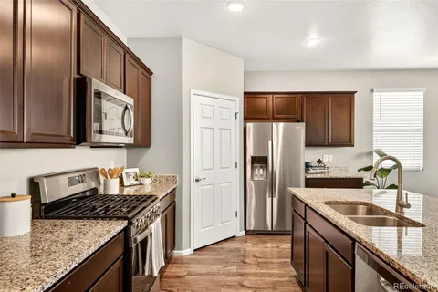 a kitchen with stainless steel appliances granite countertop a sink stove microwave and refrigerator