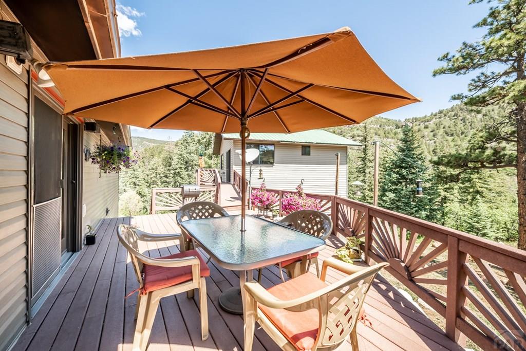 9600 Middle Creek Canyon Road Beulah, CO 81023 - Photo 3 of 50 a patio with wooden floor a yard a table and chairs