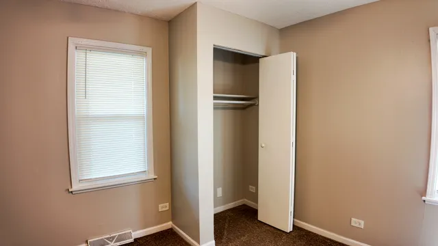 a view of an empty room with closet and a window