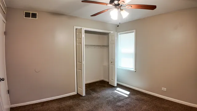 an empty room with windows and fan