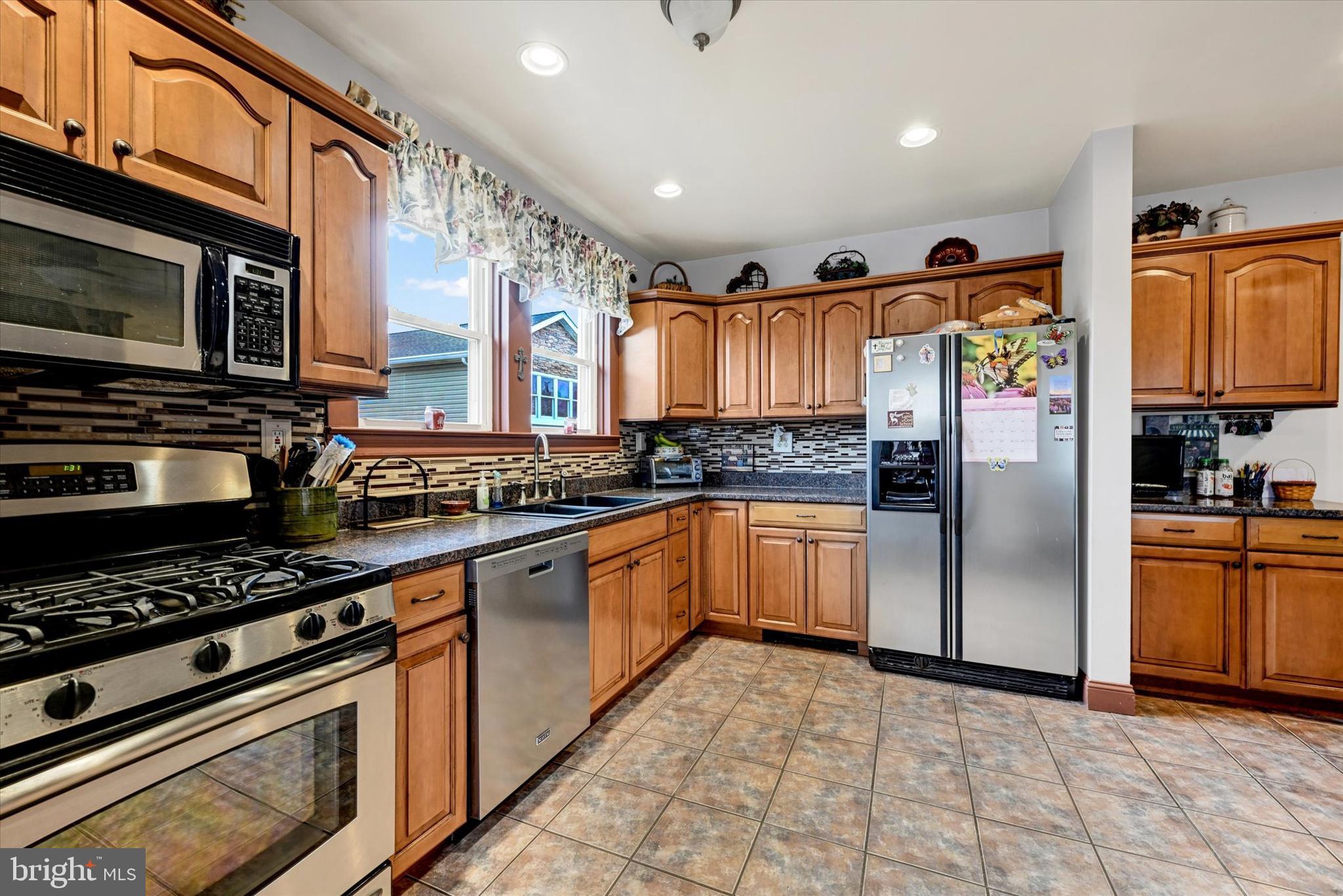 4630 Magnolia Avenue Baltimore, MD 21227 - Photo 12 of 31 a kitchen with stainless steel appliances granite countertop a stove top oven a refrigerator and a microwave
