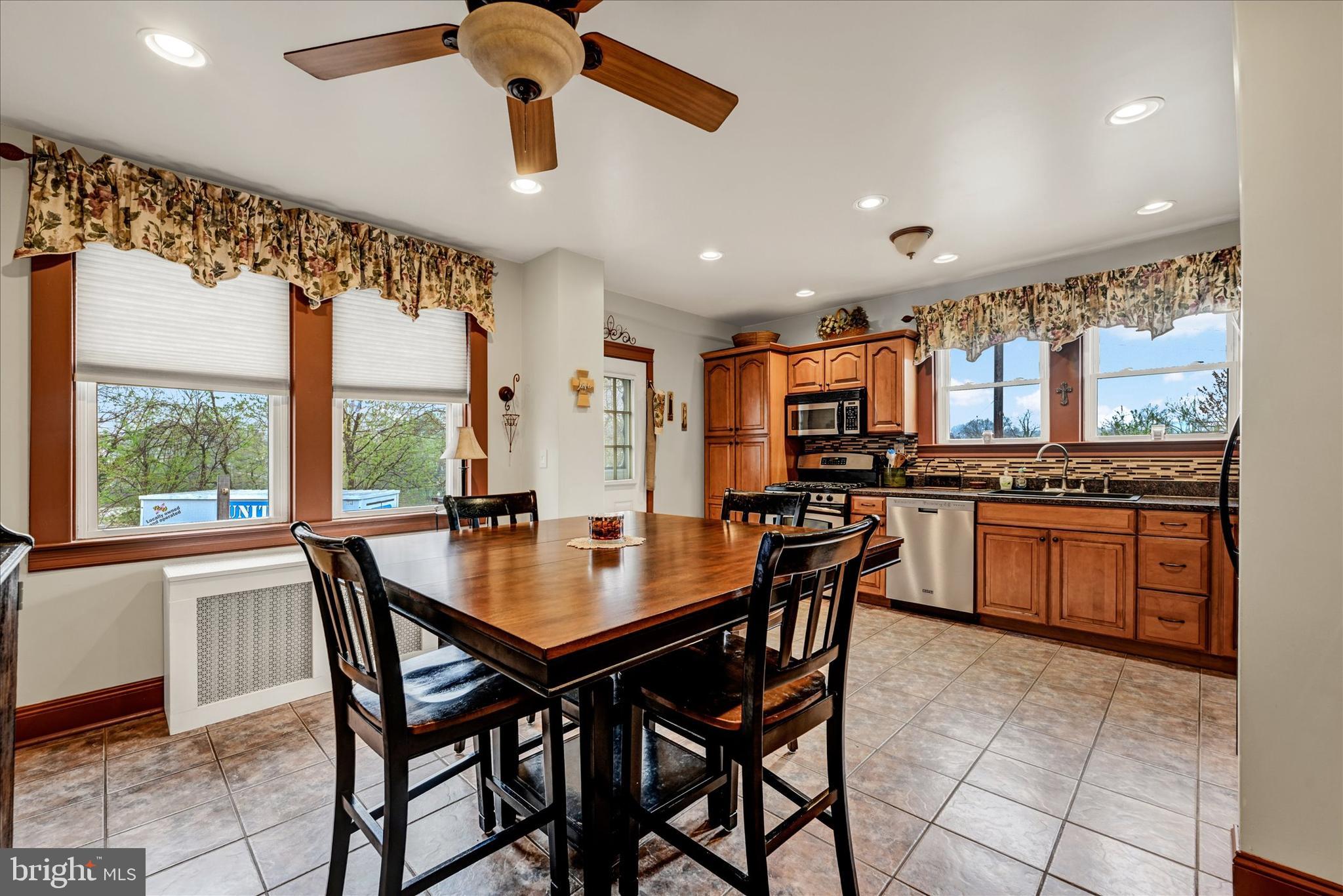 4630 Magnolia Avenue Baltimore, MD 21227 - Photo 8 of 31 a dining room with stainless steel appliances kitchen island granite countertop a stove a sink a dining table and chairs