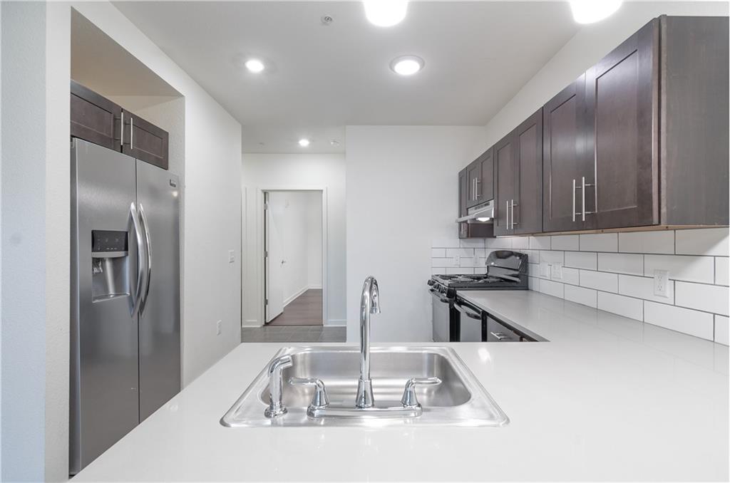 a kitchen with stainless steel appliances granite countertop a sink and a refrigerator