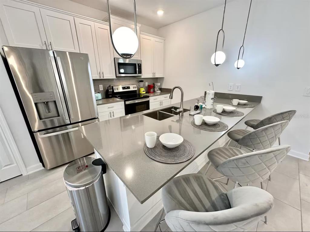 2580 Reading Trail Kissimmee, FL 34746 - Photo 11 of 34 a kitchen with sink refrigerator dining table and chairs