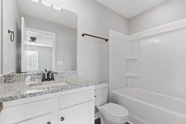 a bathroom with a granite countertop sink a toilet and bathtub
