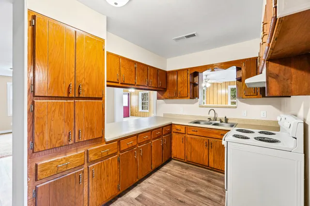 a kitchen with stainless steel appliances a sink cabinets and a window