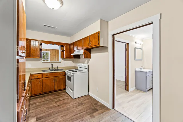 a kitchen with stainless steel appliances granite countertop a refrigerator a stove top oven a sink and dishwasher with wooden floor