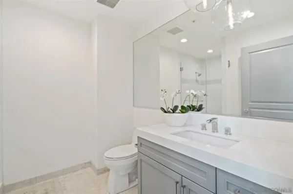 a bathroom with a granite countertop sink vanity mirror and toilet