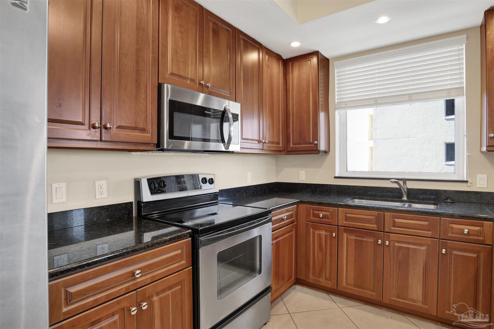 608 Lost Key Drive, Unit 701C Pensacola, FL 32507 - Photo 12 of 32 a kitchen with granite countertop cabinets stainless steel appliances and a sink