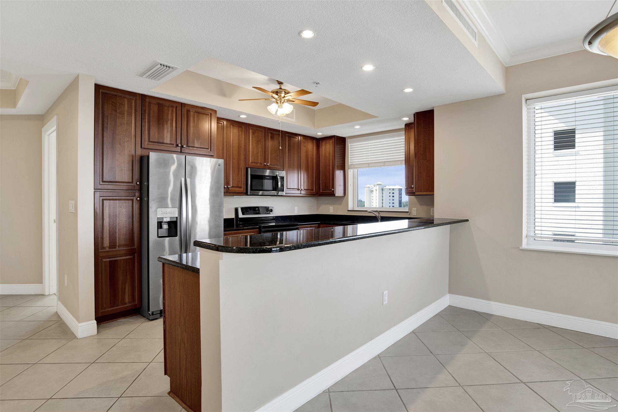 608 Lost Key Drive, Unit 701C Pensacola, FL 32507 - Photo 14 of 32 a kitchen with stainless steel appliances granite countertop a refrigerator a stove a sink and a microwave