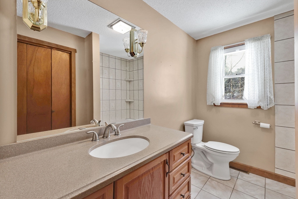 433 Ventura Street Ludlow, MA 01056 - Photo 13 of 39 a bathroom with a granite countertop sink a toilet and a mirror