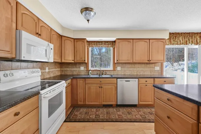 a kitchen with granite countertop cabinets stainless steel appliances a sink and a window