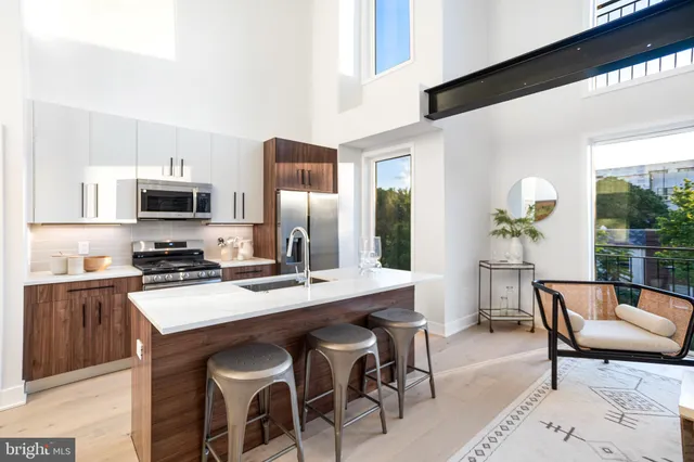 a dining room with furniture wooden floor and a kitchen view