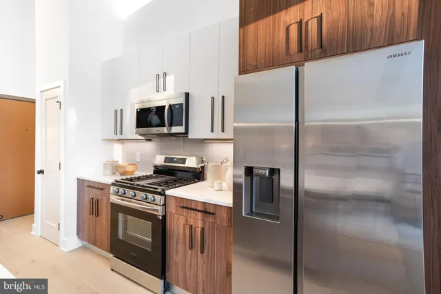a kitchen with a refrigerator a microwave a sink and cabinets