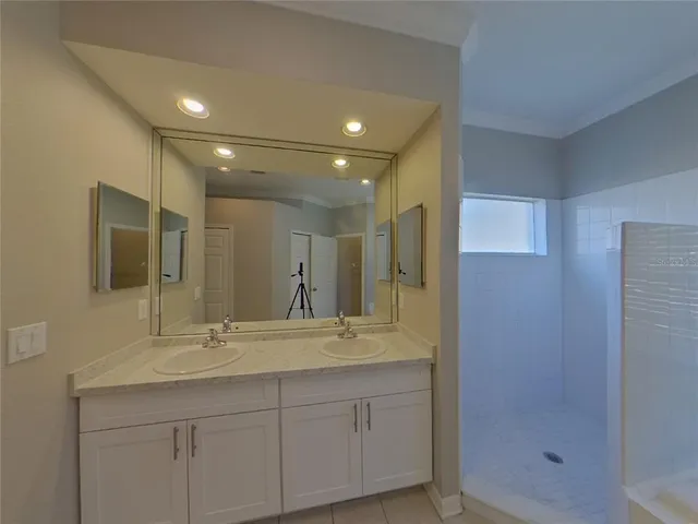 a bathroom with double sink shower and two mirror