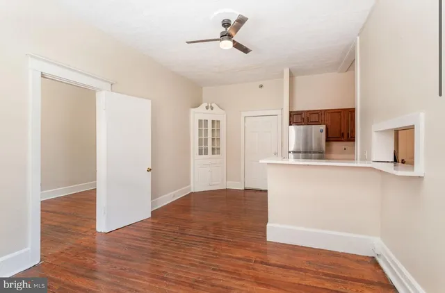 a view of empty room with wooden floor and kitchen view