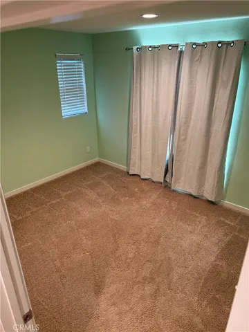 a view of an empty room with closet and a window