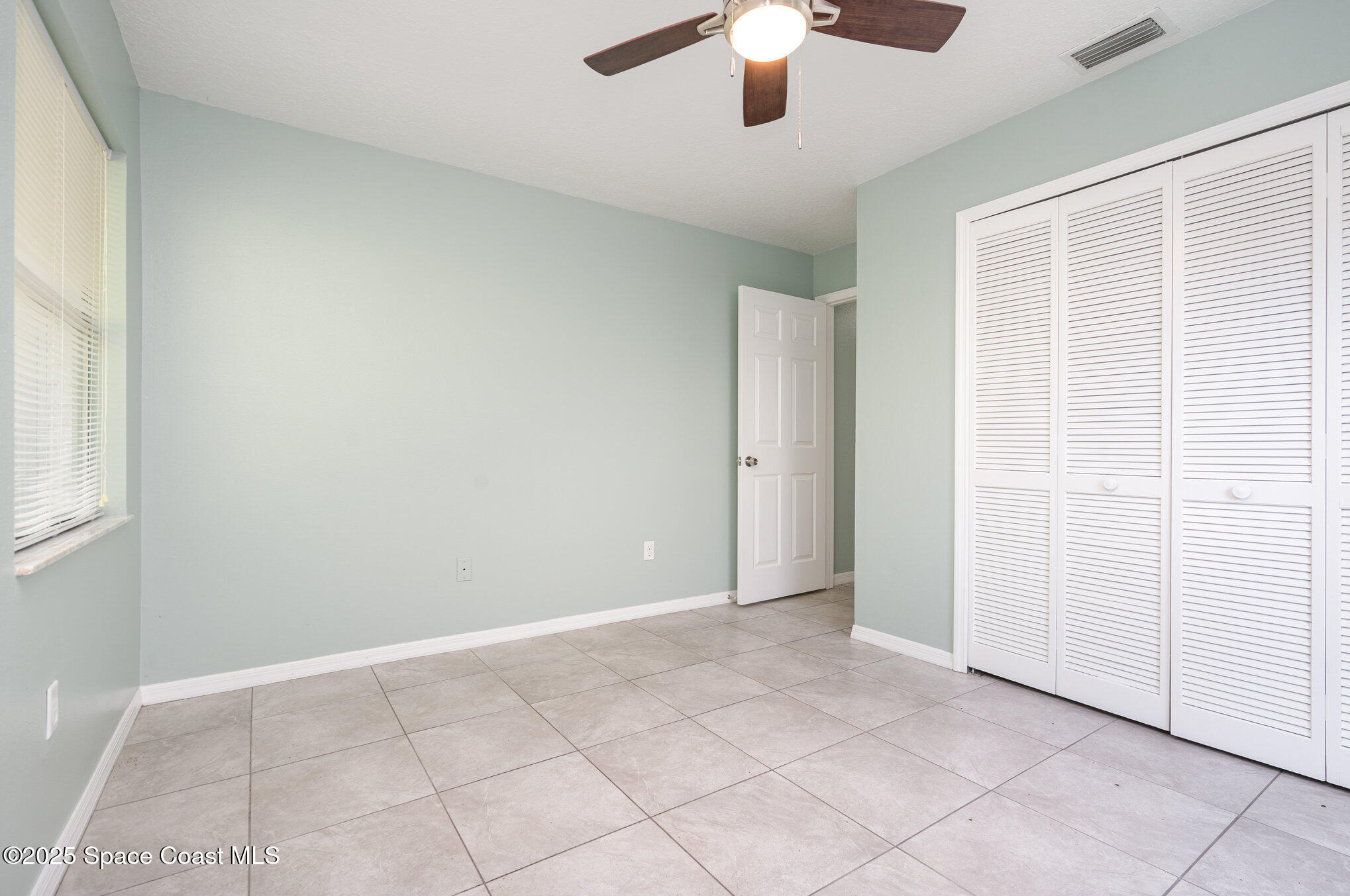 636 Fishtail Palm Boulevard Melbourne, FL 32901 - Photo 21 of 25 an empty room with chandelier fan and windows