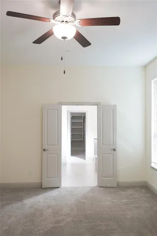 an empty room with chandelier fan and windows