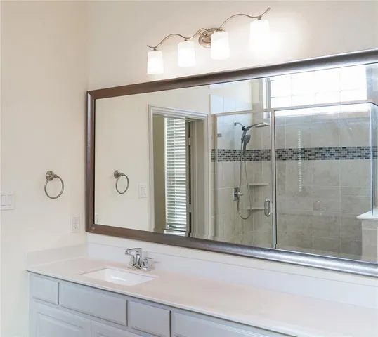 a bathroom with a shower sink and mirror